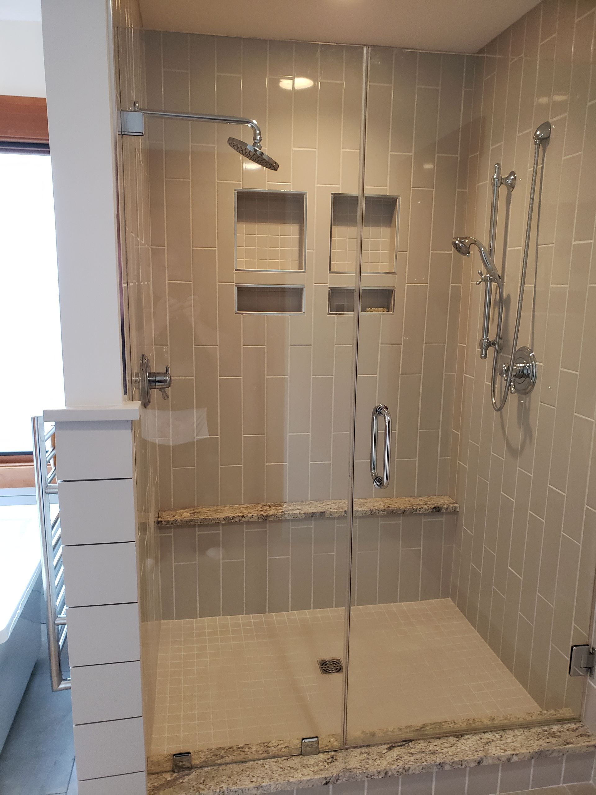 A bathroom with a walk-in shower with a glass door