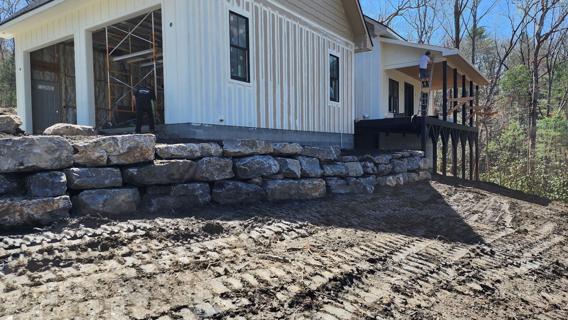A stone wall is being built in front of a house.