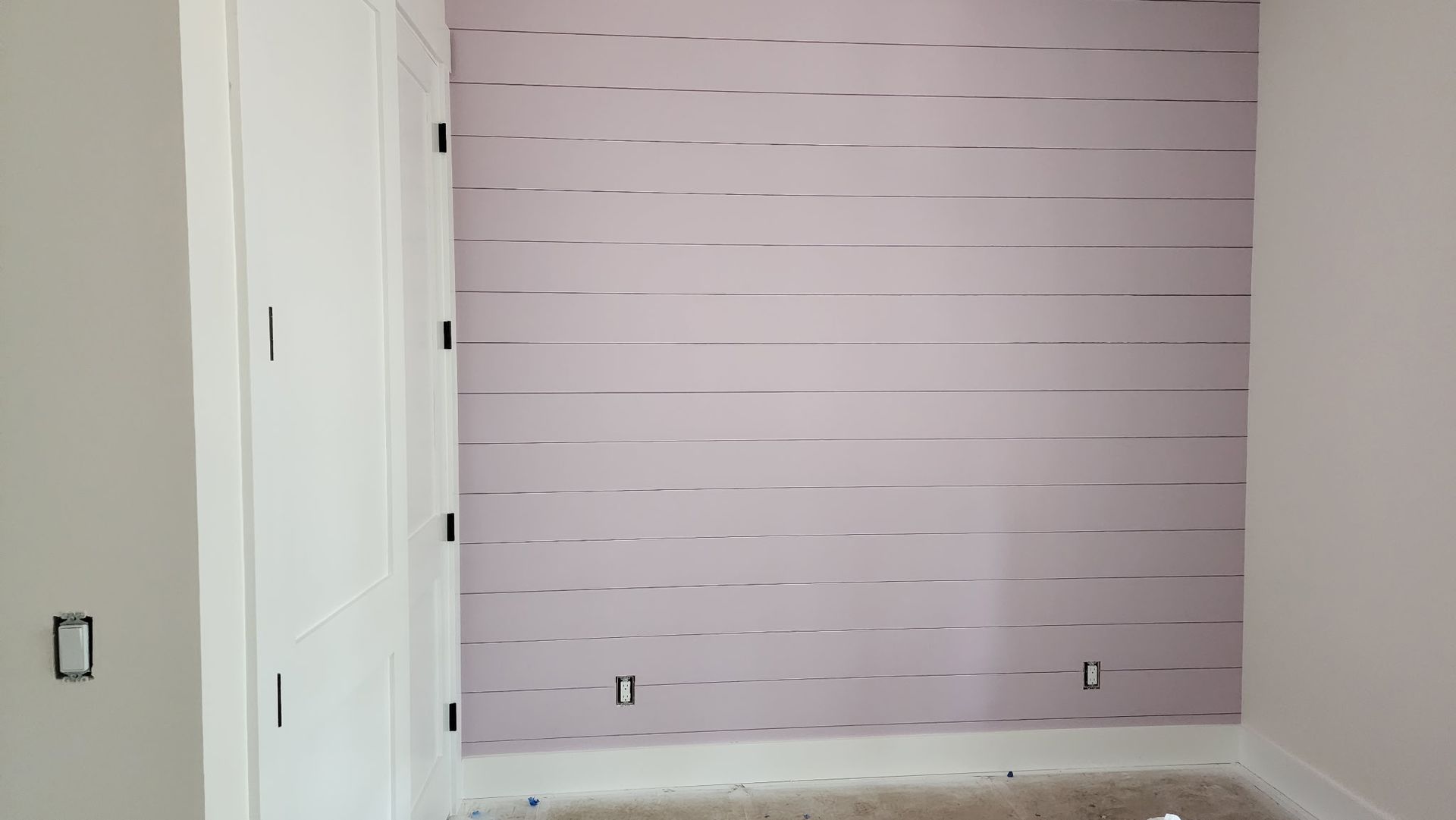 A room with a purple wall and a white door.