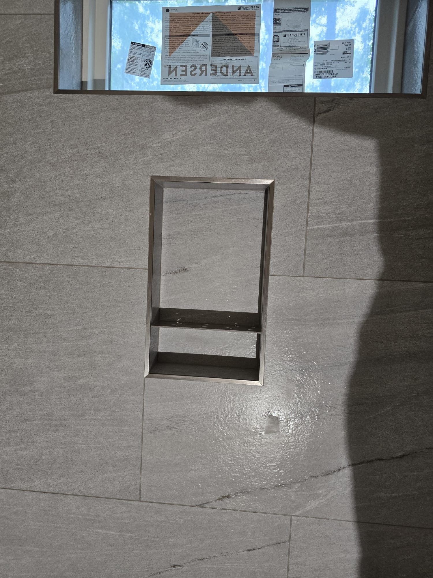 A shadow of a person is cast on a tiled wall