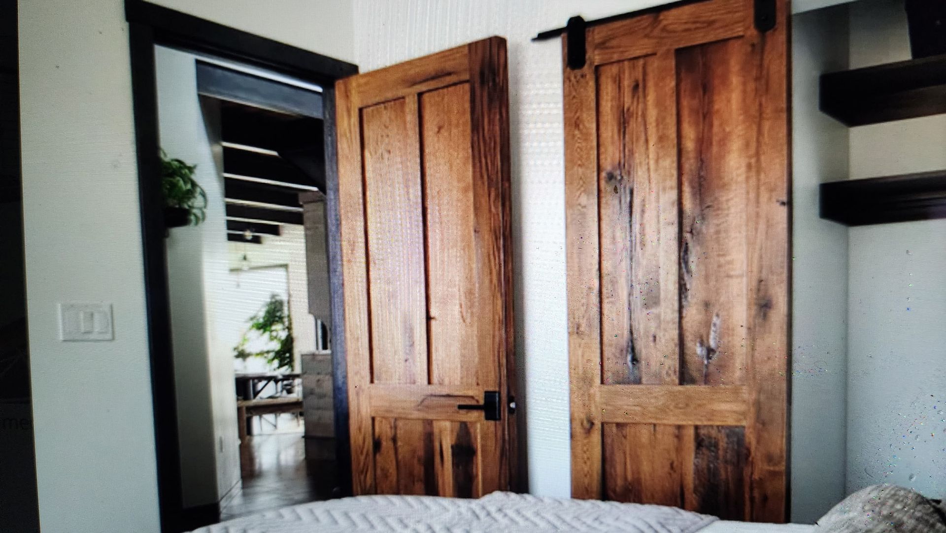 A bedroom with two wooden sliding barn doors and a bed.