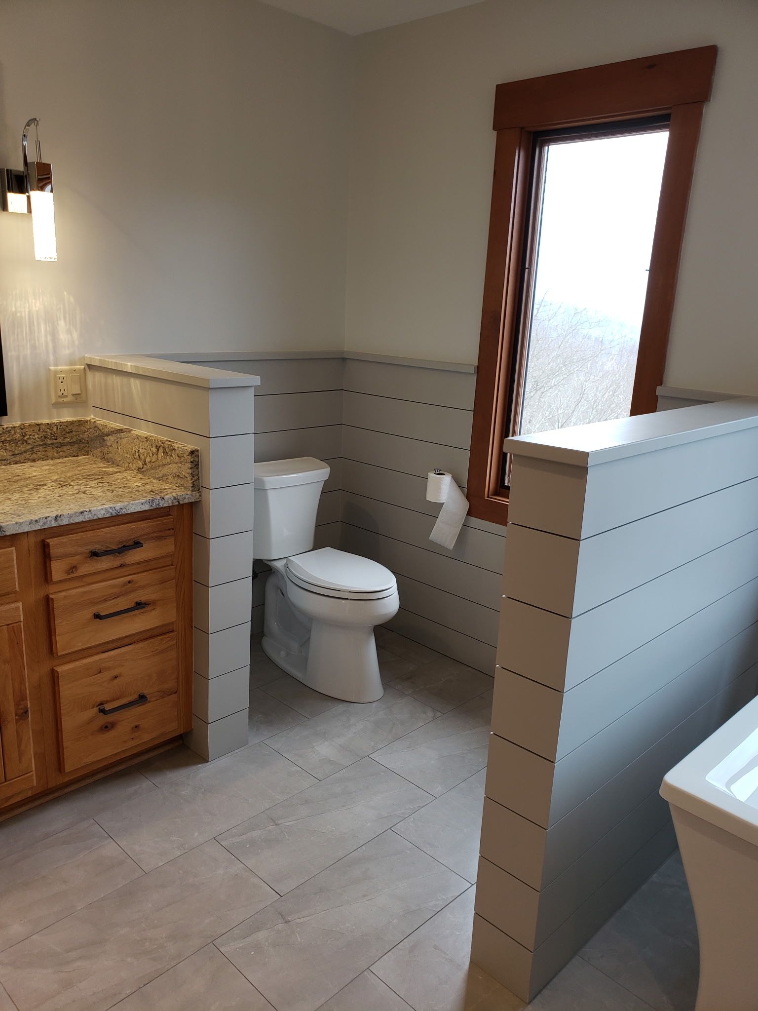 A bathroom with a toilet , sink , and window.