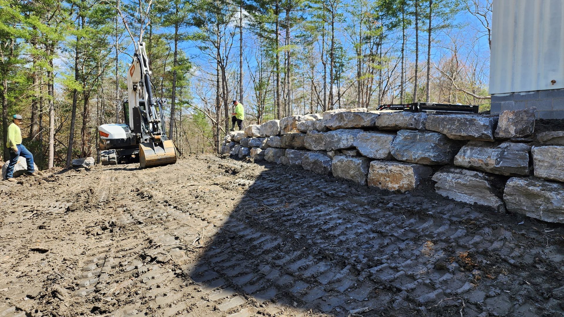 A large rock wall is being built in the middle of a dirt field.