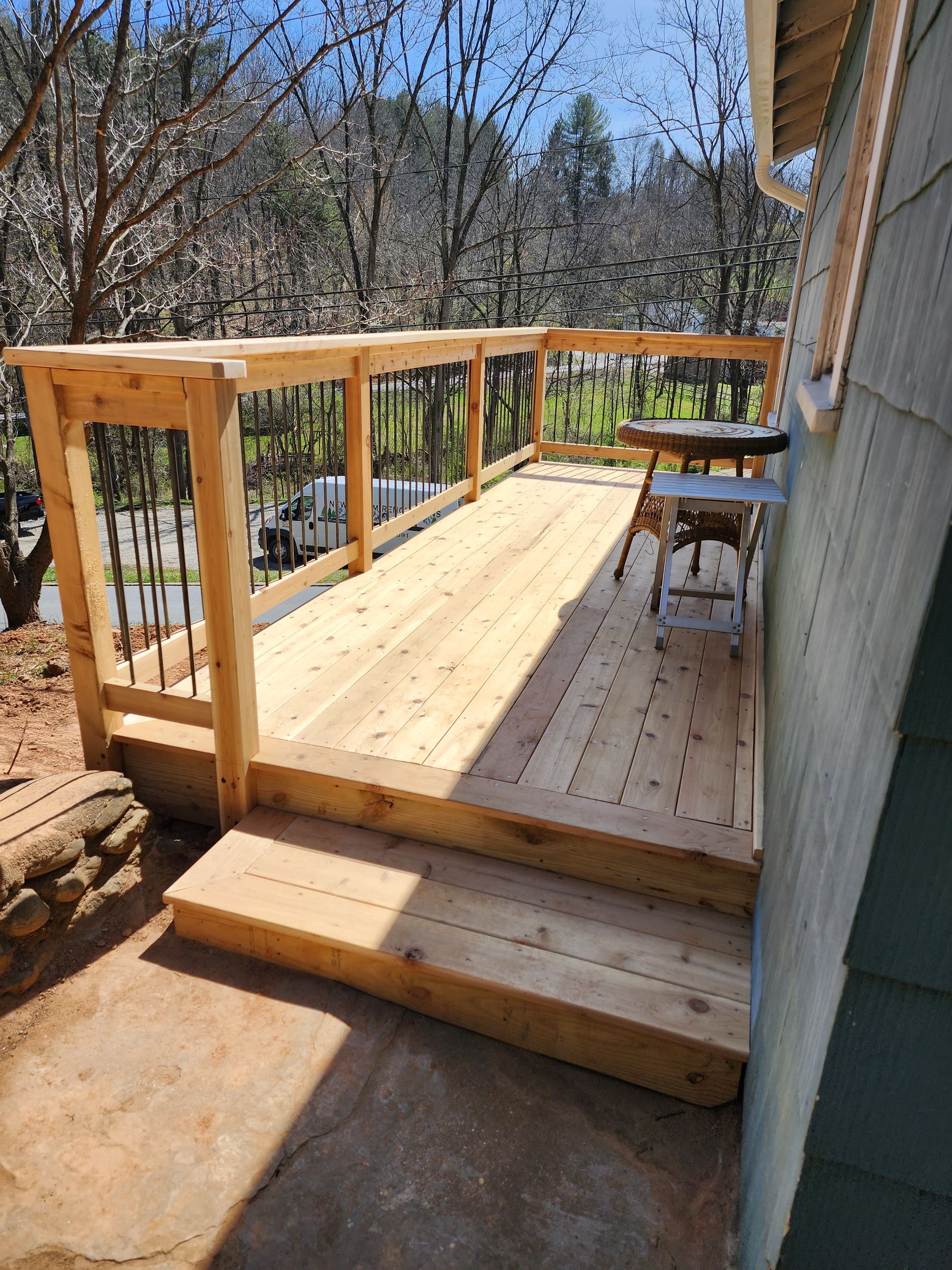 A wooden deck with stairs leading up to it is next to a house