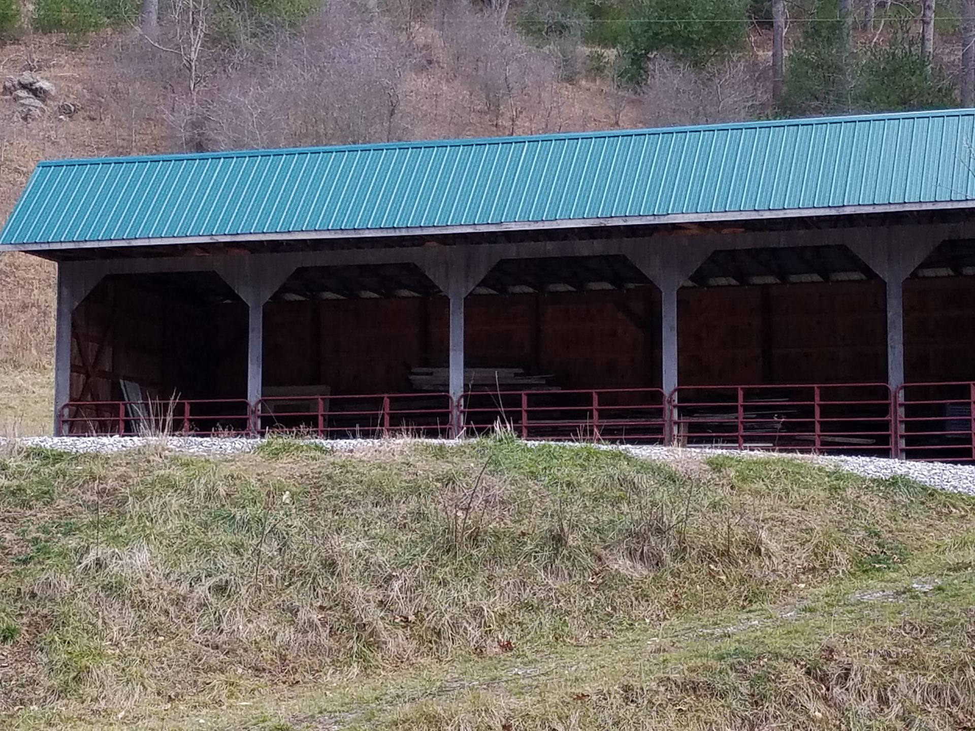 A barn with a green roof and a fence around it