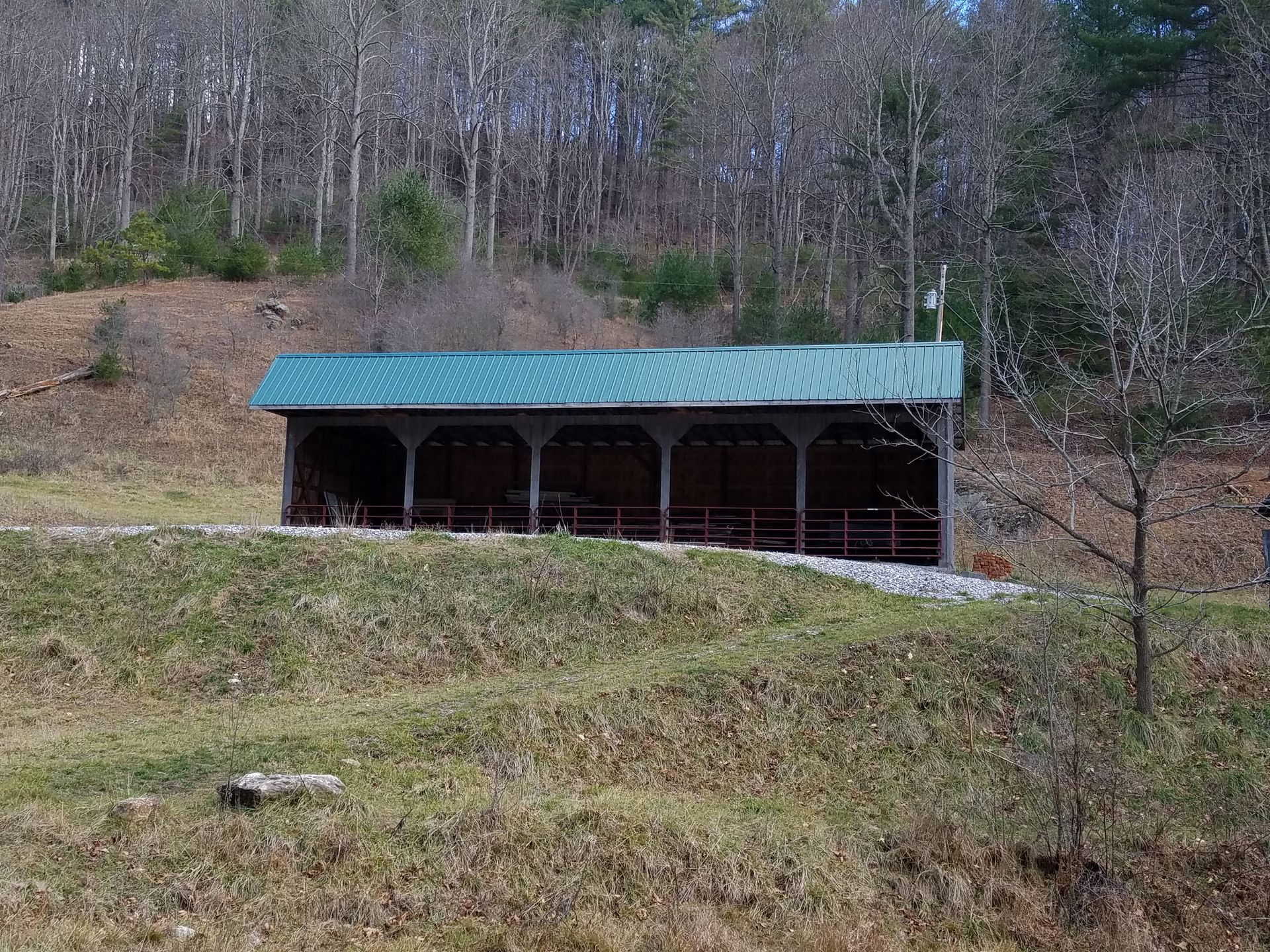 A shed with a green roof is in the middle of a field