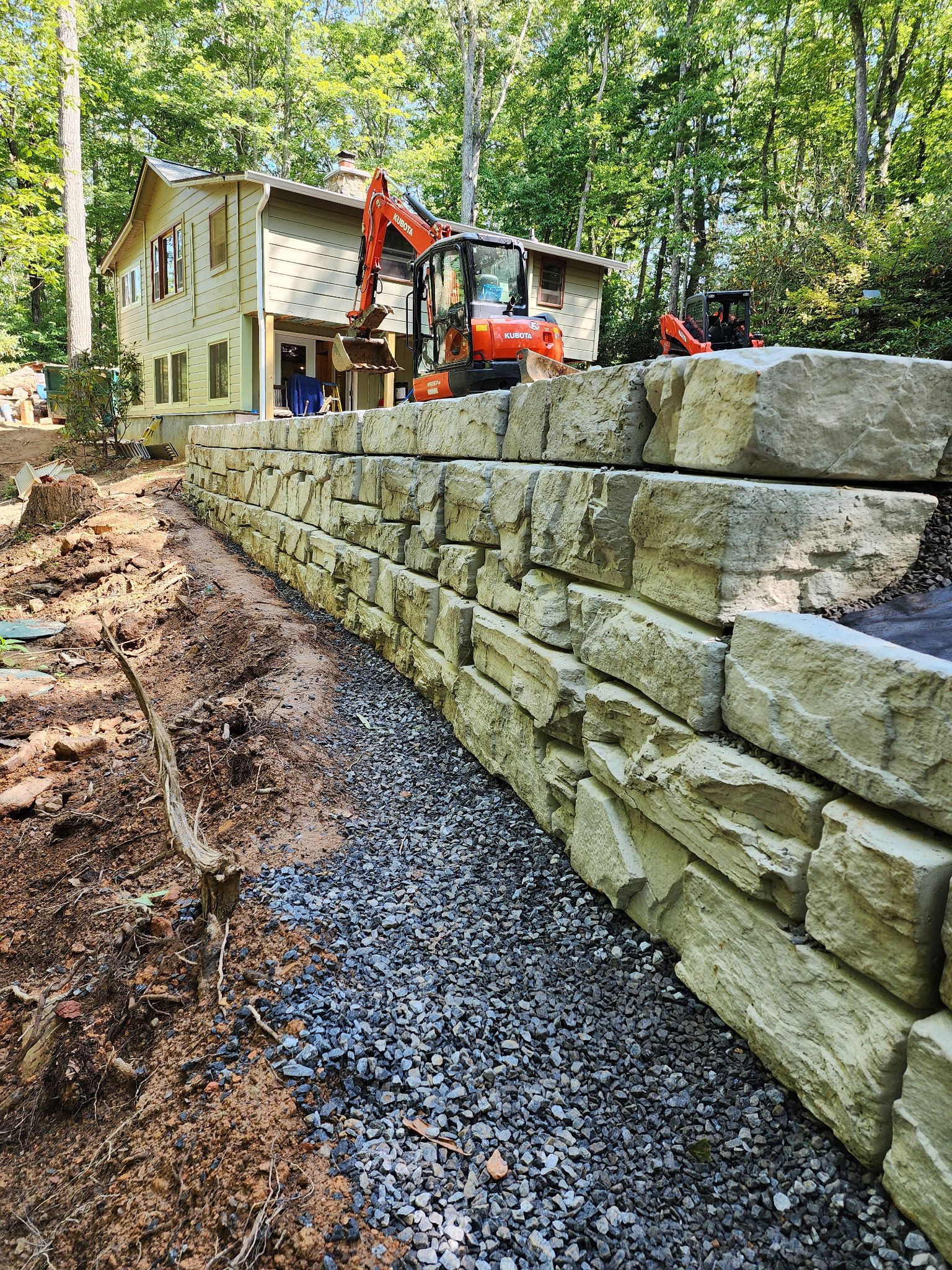 A large stone wall is being built in front of a house