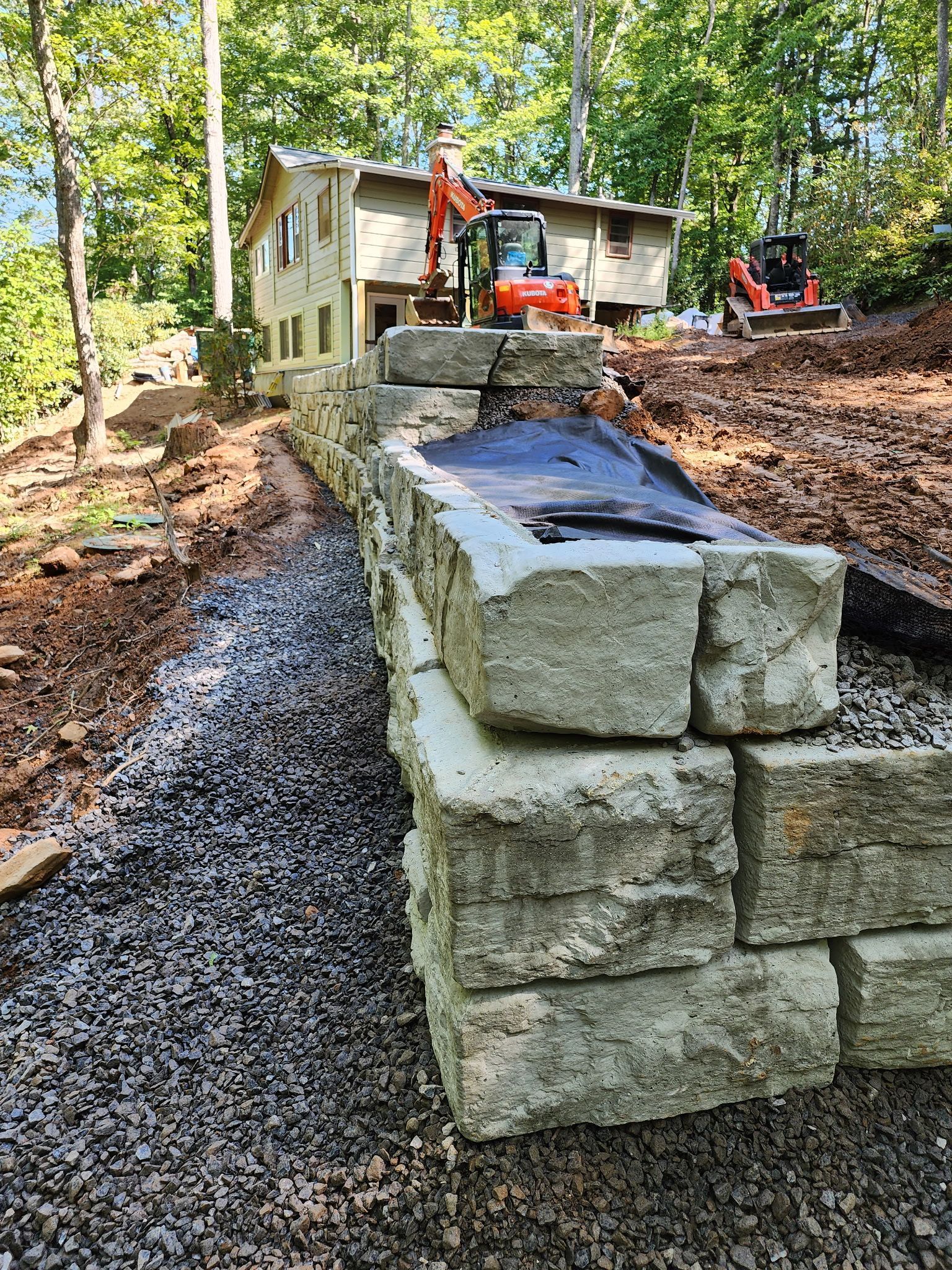 A stack of bricks is sitting on top of gravel in front of a house