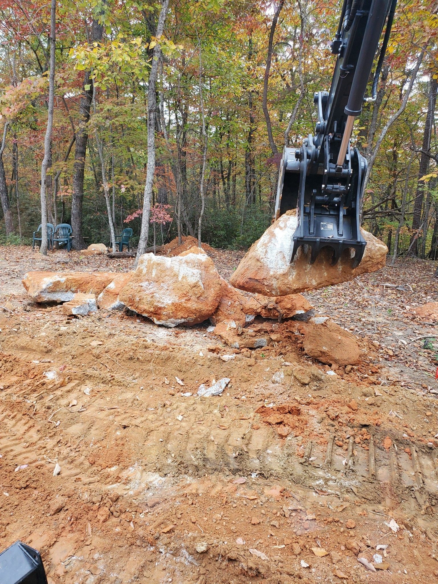 A large rock is being lifted by a crane in a dirt field