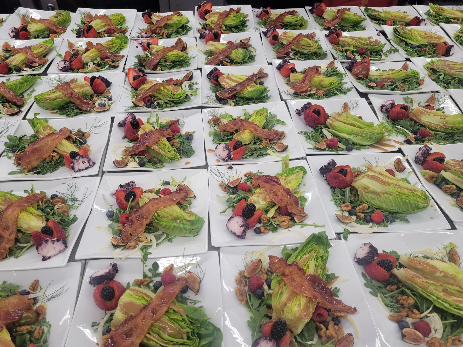 Plated salmon salads arranged in rows on a white table at an event or catering buffet