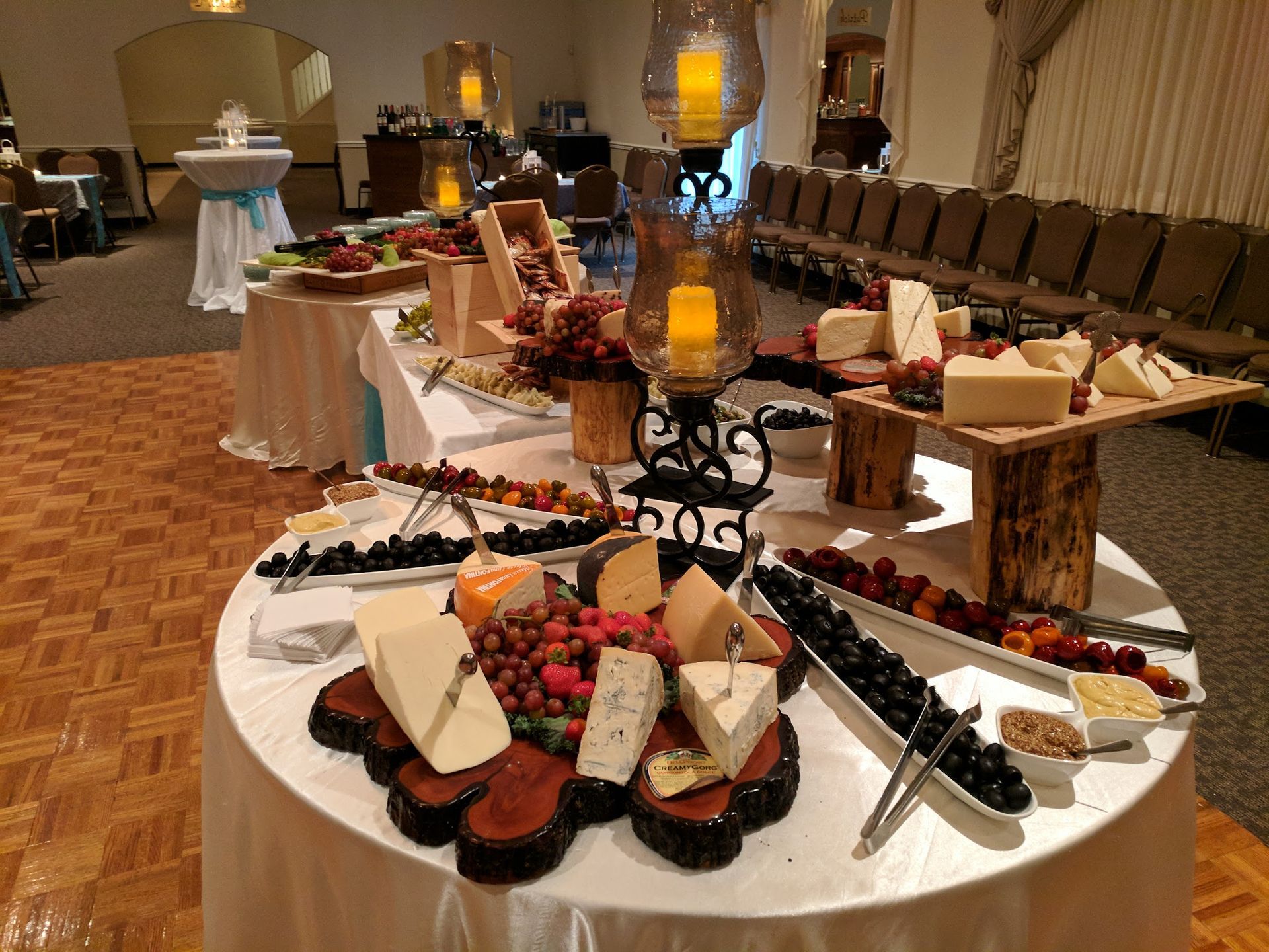 Banquet hall buffet table with desserts, cheese, and candles on white tablecloths