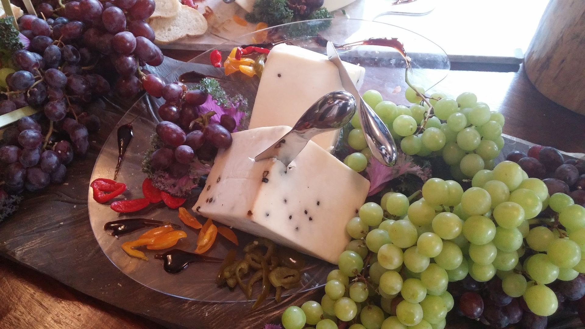 Assorted grapes and wedges of cheese on a serving tray, with nuts and colorful garnish