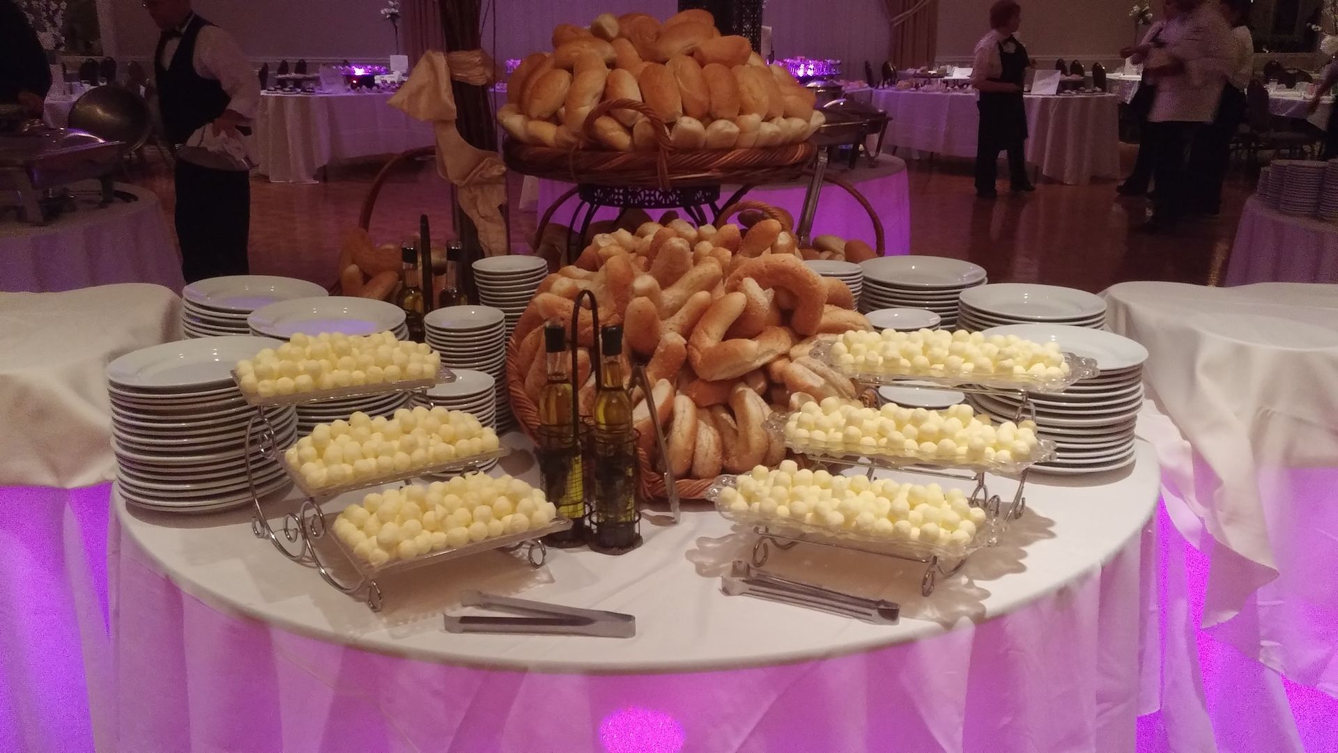 Buffet table with pastries and cookies on white platters under purple lighting