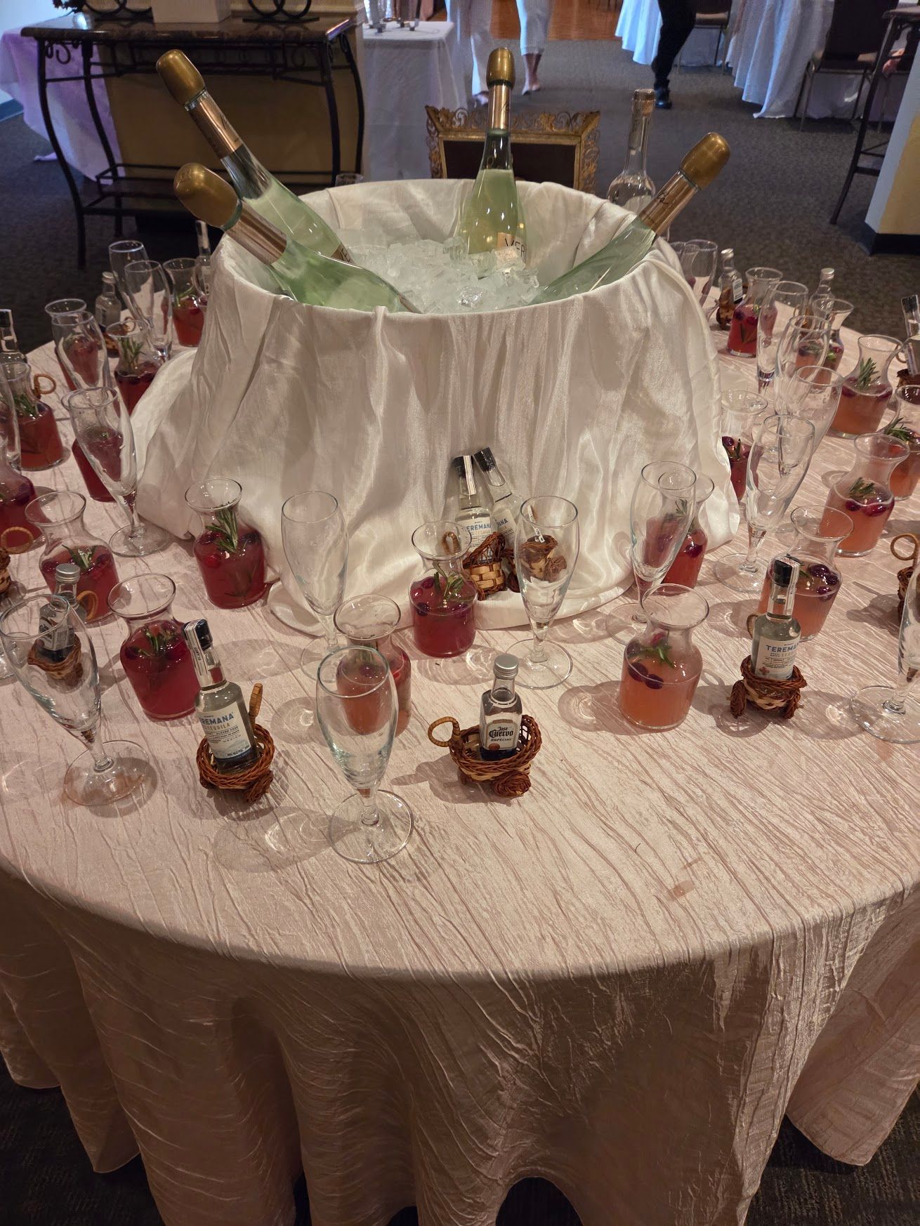 Round banquet table with a draped champagne bucket centerpiece and small dessert shots arranged around it.