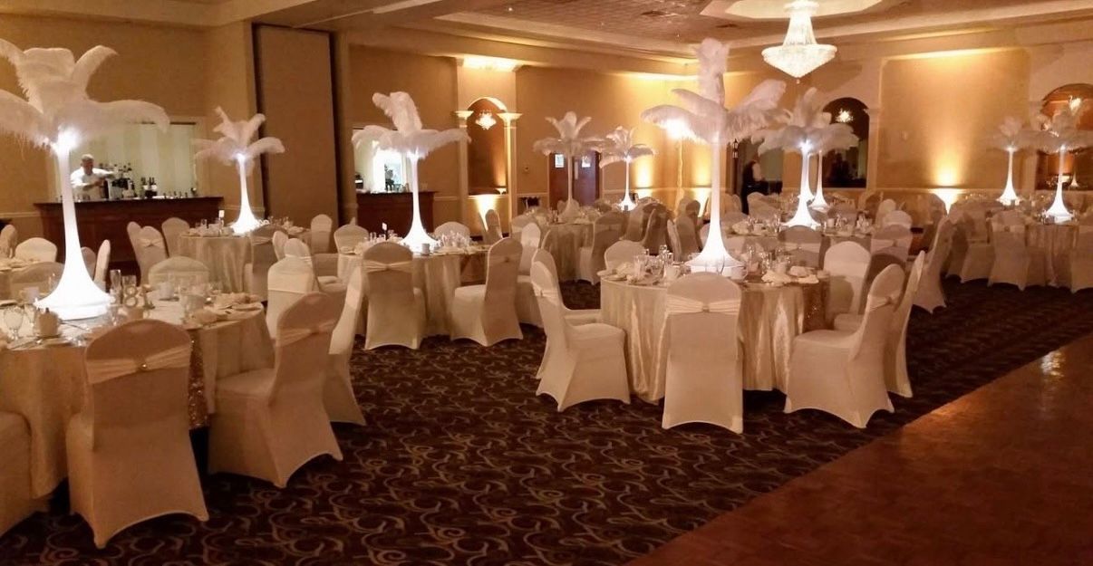 Elegant banquet hall with round tables, white chair covers, and warm ambient lighting