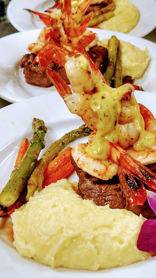 Plated seafood dish with shrimp, creamy mashed potatoes, asparagus, and a yellow sauce