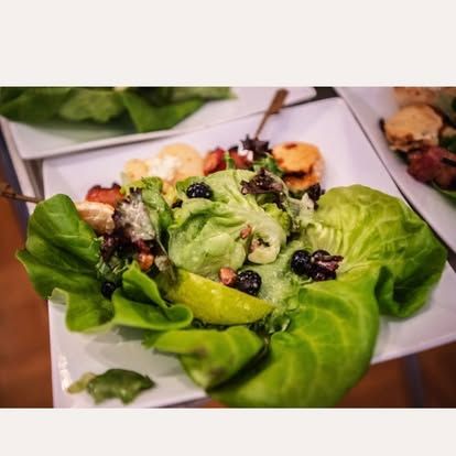 Lettuce-wrapped salad with nuts, berries, and grated cheese on a white plate