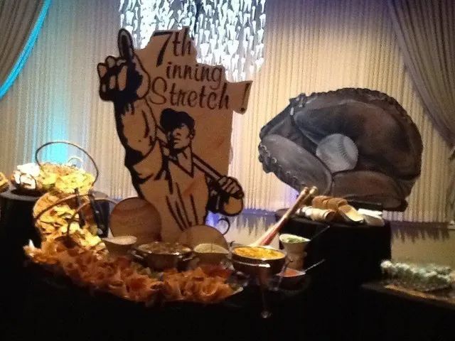 Buffet table with decorative cardboard cutouts, buffet dishes, and a large serving bowl under draped curtains
