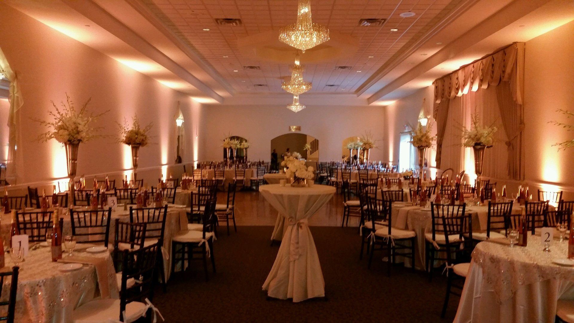 Elegant banquet hall with chandeliers, round tables, and warm lighting set for an event