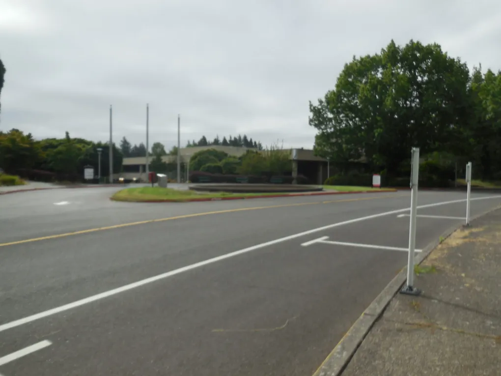 Empty road and sidewalk beside a low building on an overcast day