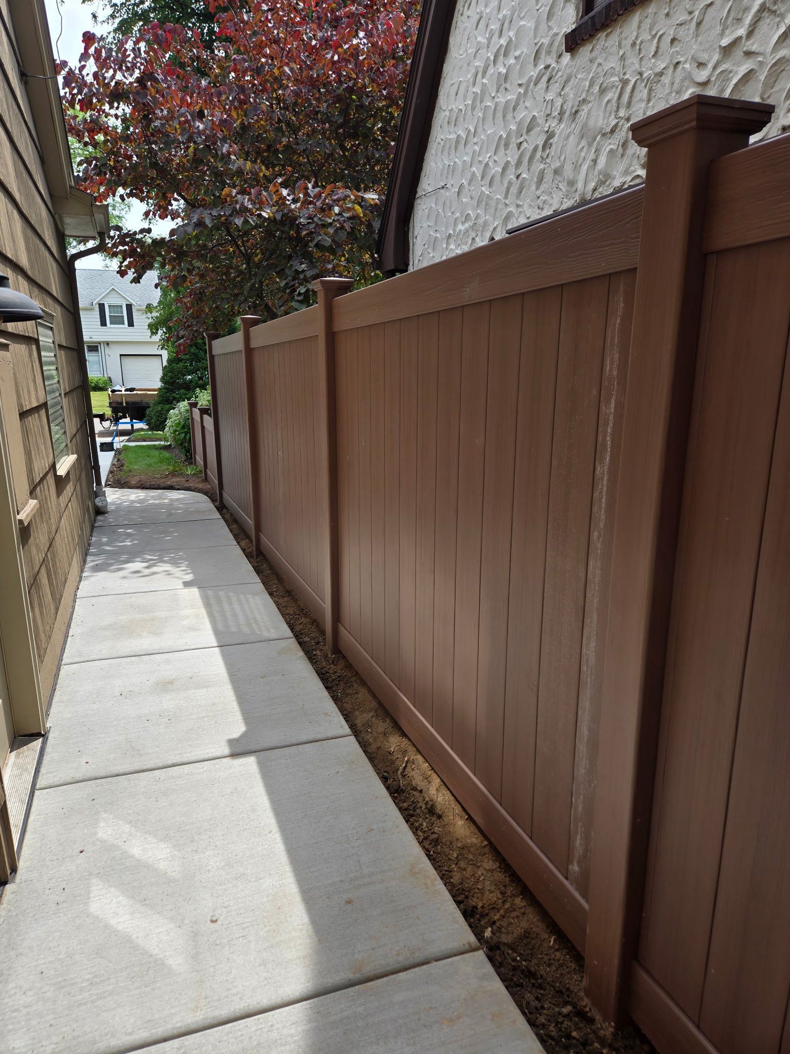A wooden fence along a sidewalk next to a house.