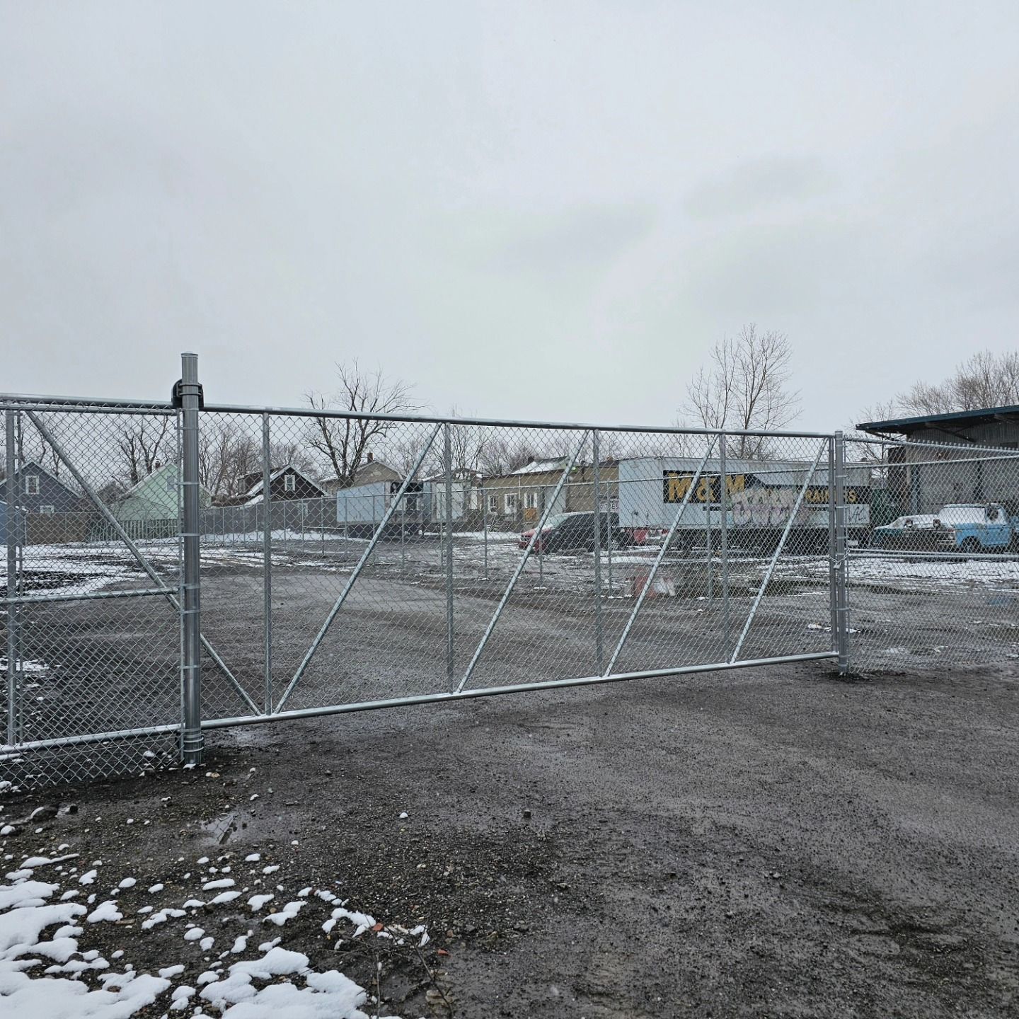 There is a chain link fence in the middle of a snowy field.