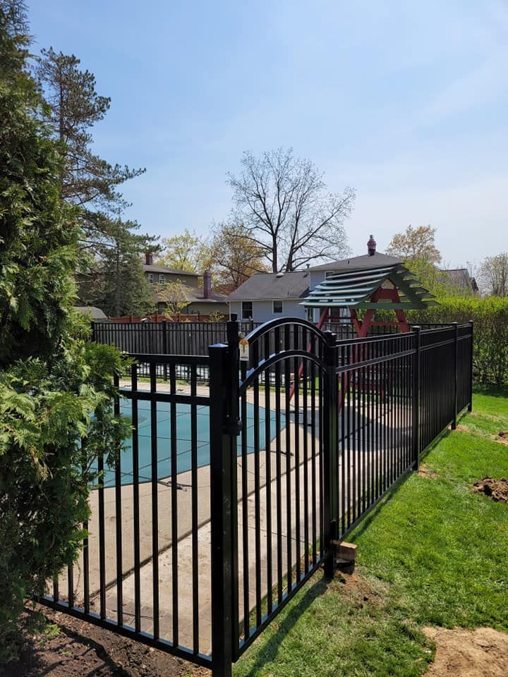 A black fence surrounds a swimming pool in a backyard.