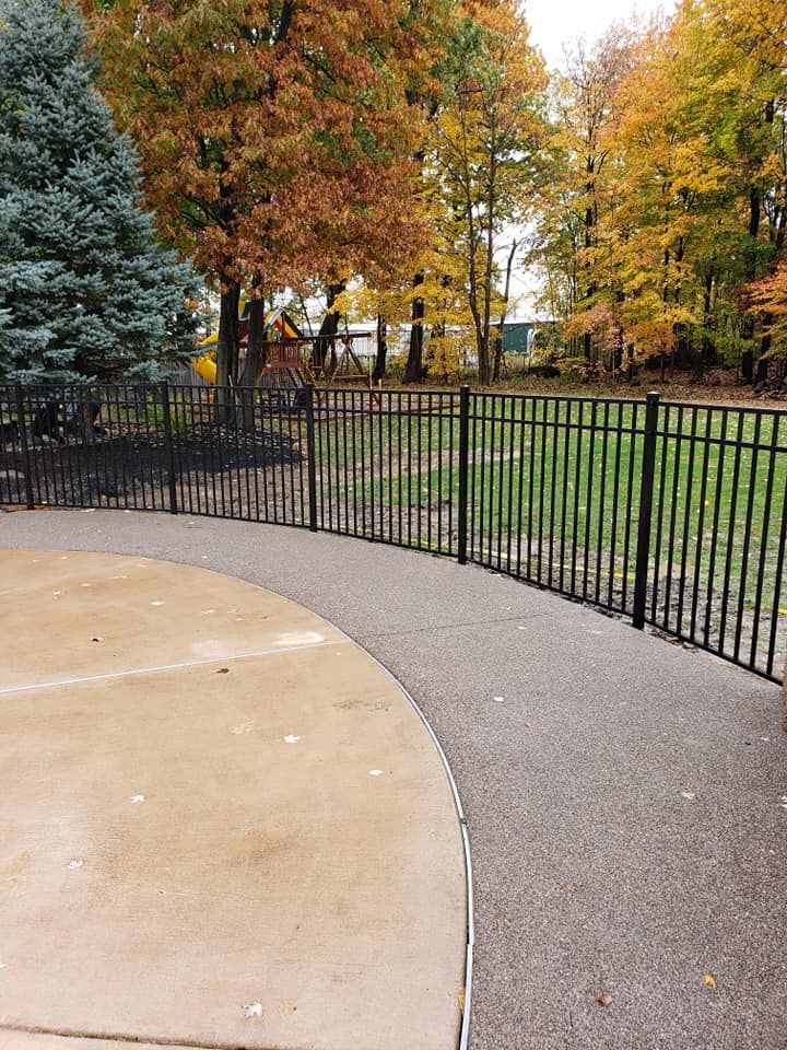 A fence surrounds a basketball court in a park