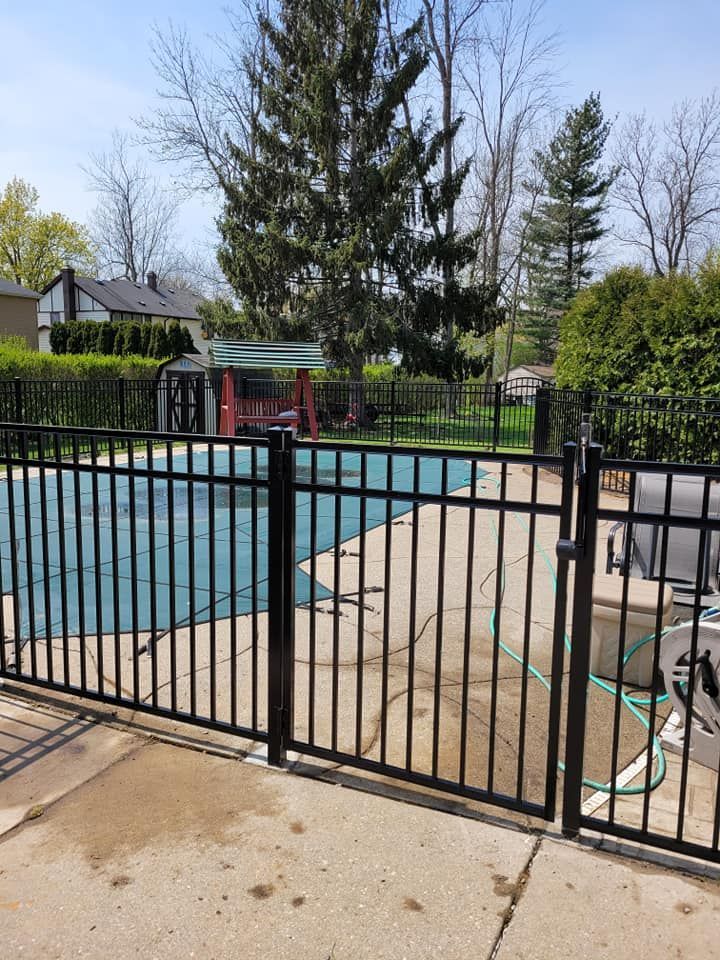 A black metal fence surrounds a swimming pool.