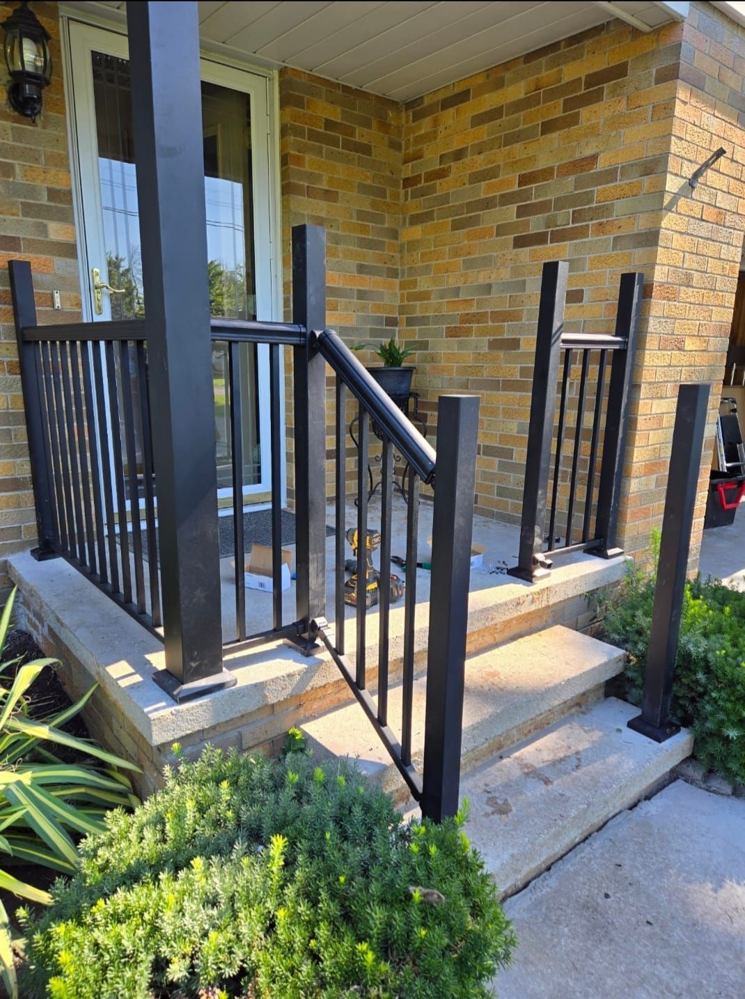 A brick house with a black railing and stairs