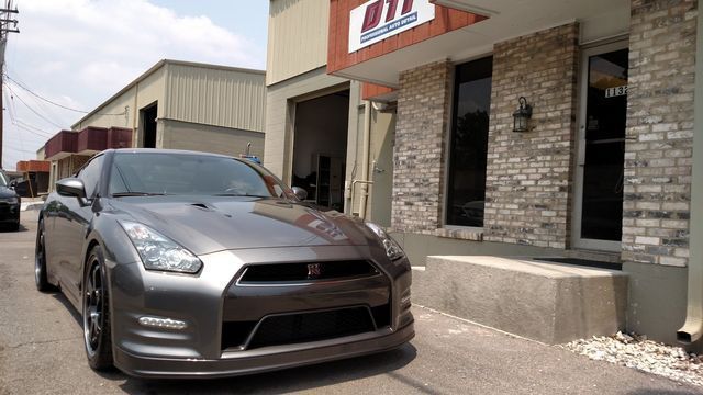 Gray Nissan GT-R parked in front of a building with a “MT” sign.