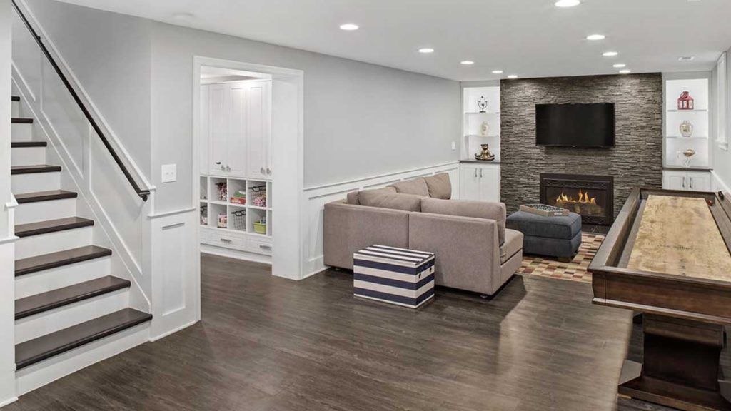 A living room with a couch, stairs, a pool table and a fireplace.