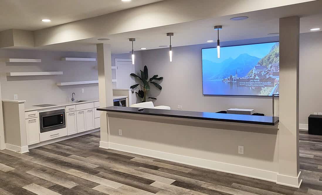 A kitchen with a large flat screen tv on the wall.