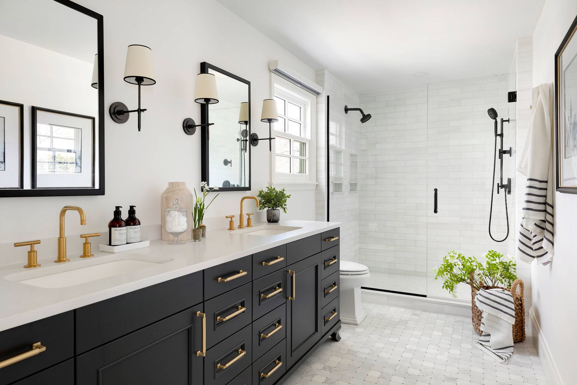A bathroom with two sinks, a toilet, and a walk in shower.