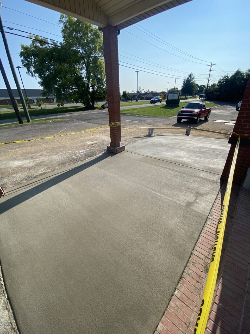 A red truck is parked on the side of the road next to a concrete walkway.