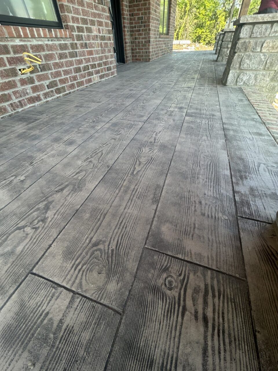 A patio with a wooden floor and a brick wall.
