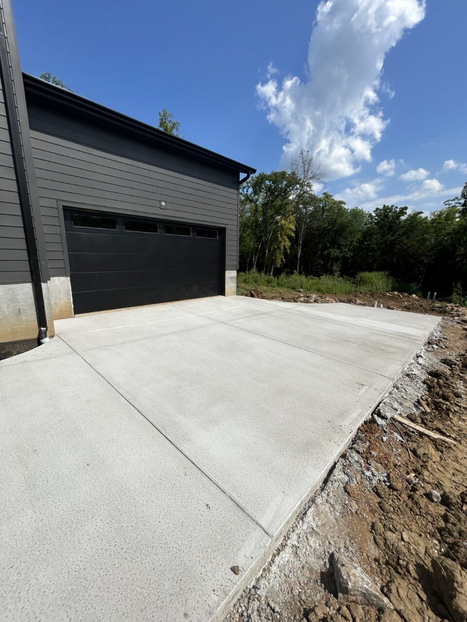 A concrete driveway leading to a garage with a black garage door.