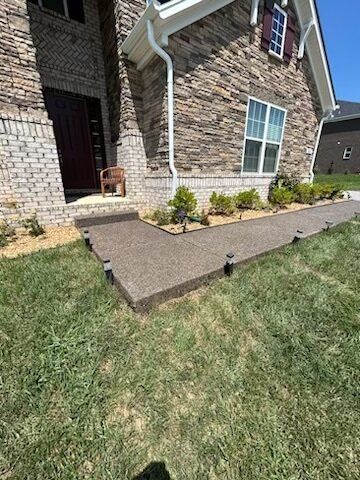A brick house with a concrete walkway leading to the front door.