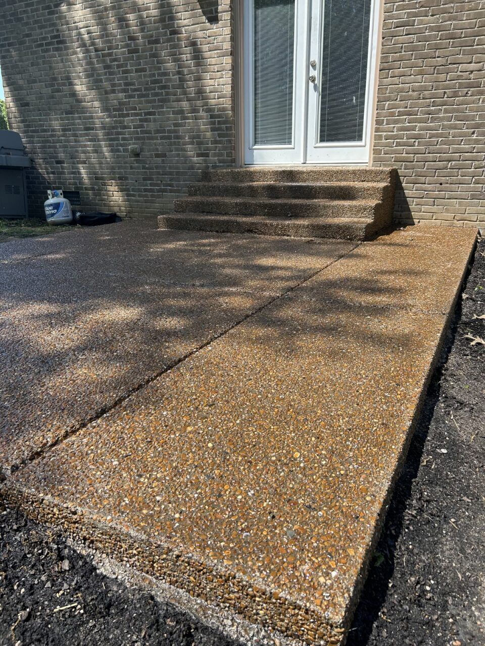 A brick house with a concrete walkway and stairs in front of it.