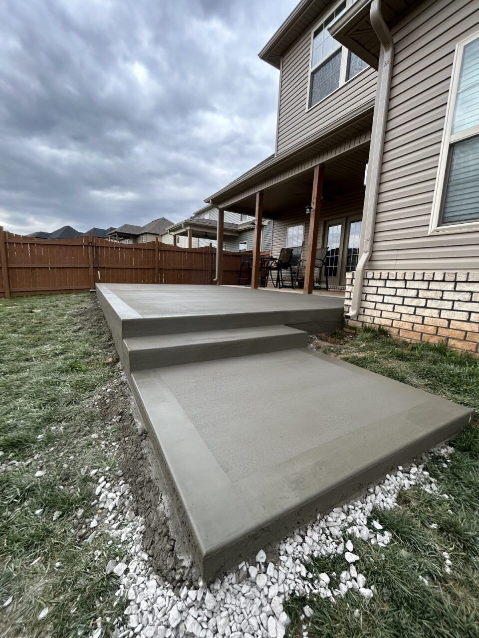 A concrete walkway leading to a patio in front of a house.