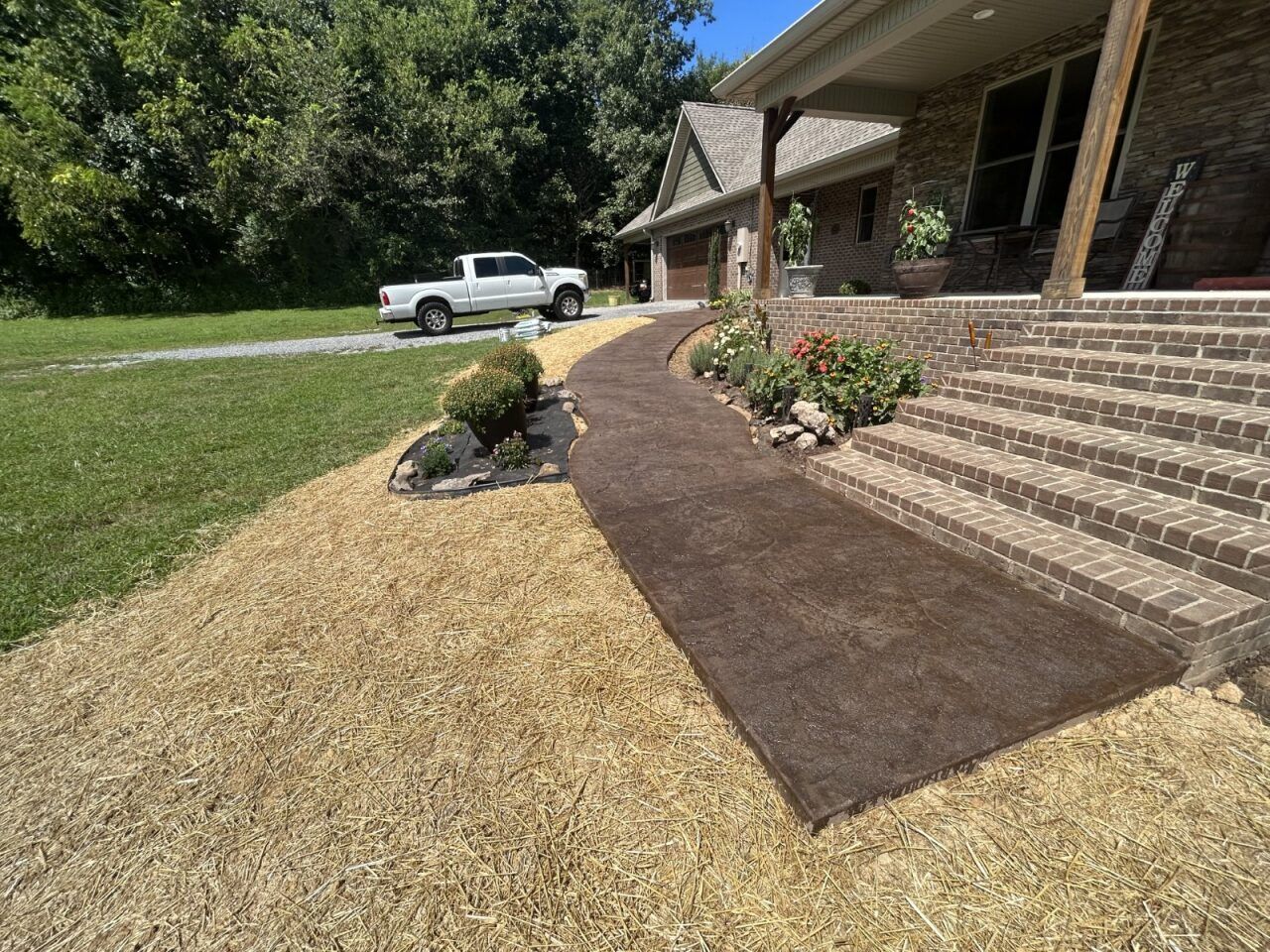A white truck is parked on the side of the road in front of a house.