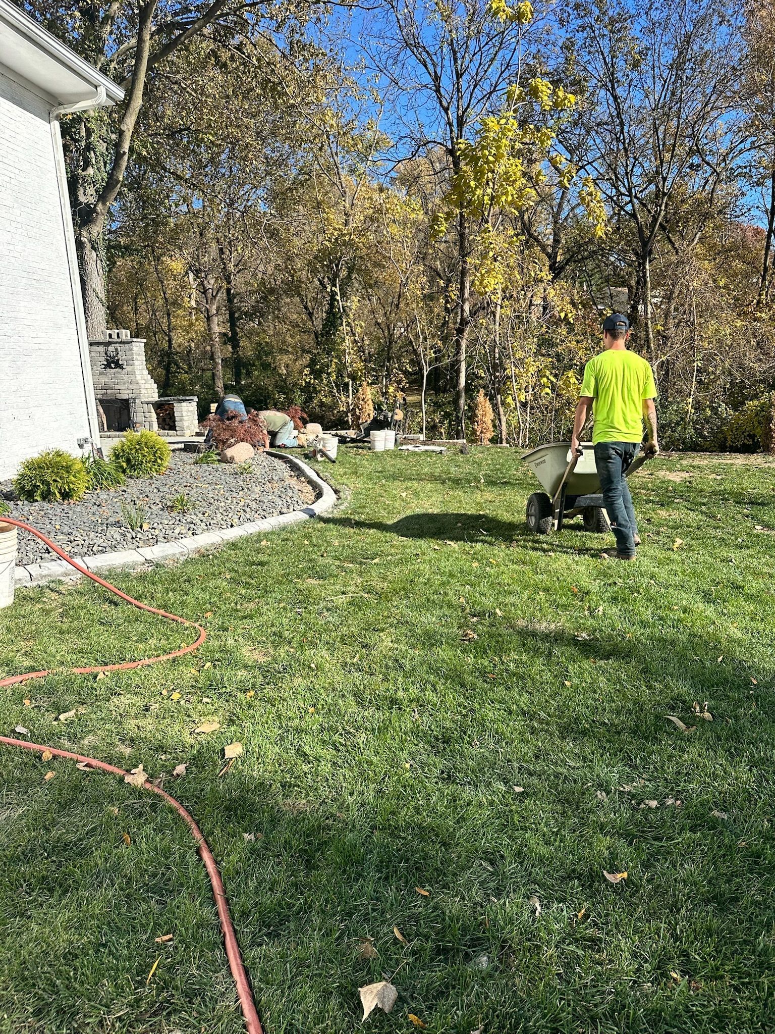 Person mowing a green lawn beside a house on a sunny day