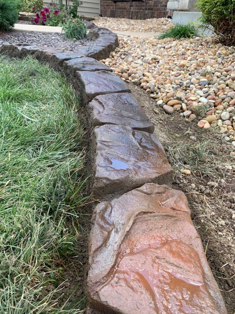 Stone garden path bordered by grass and pebbles, leading uphill through a landscaped yard