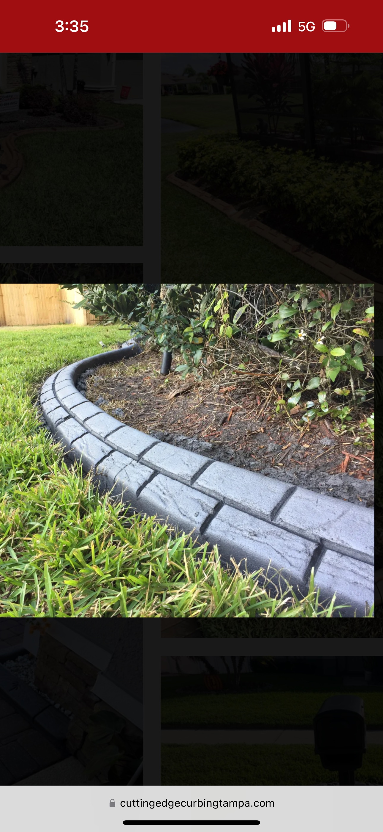Curved gray stone garden edging beside mulch and green grass in a landscaped yard