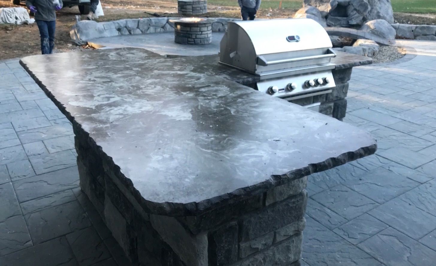 Outdoor stone countertop with built-in stainless steel grill in a patio setting