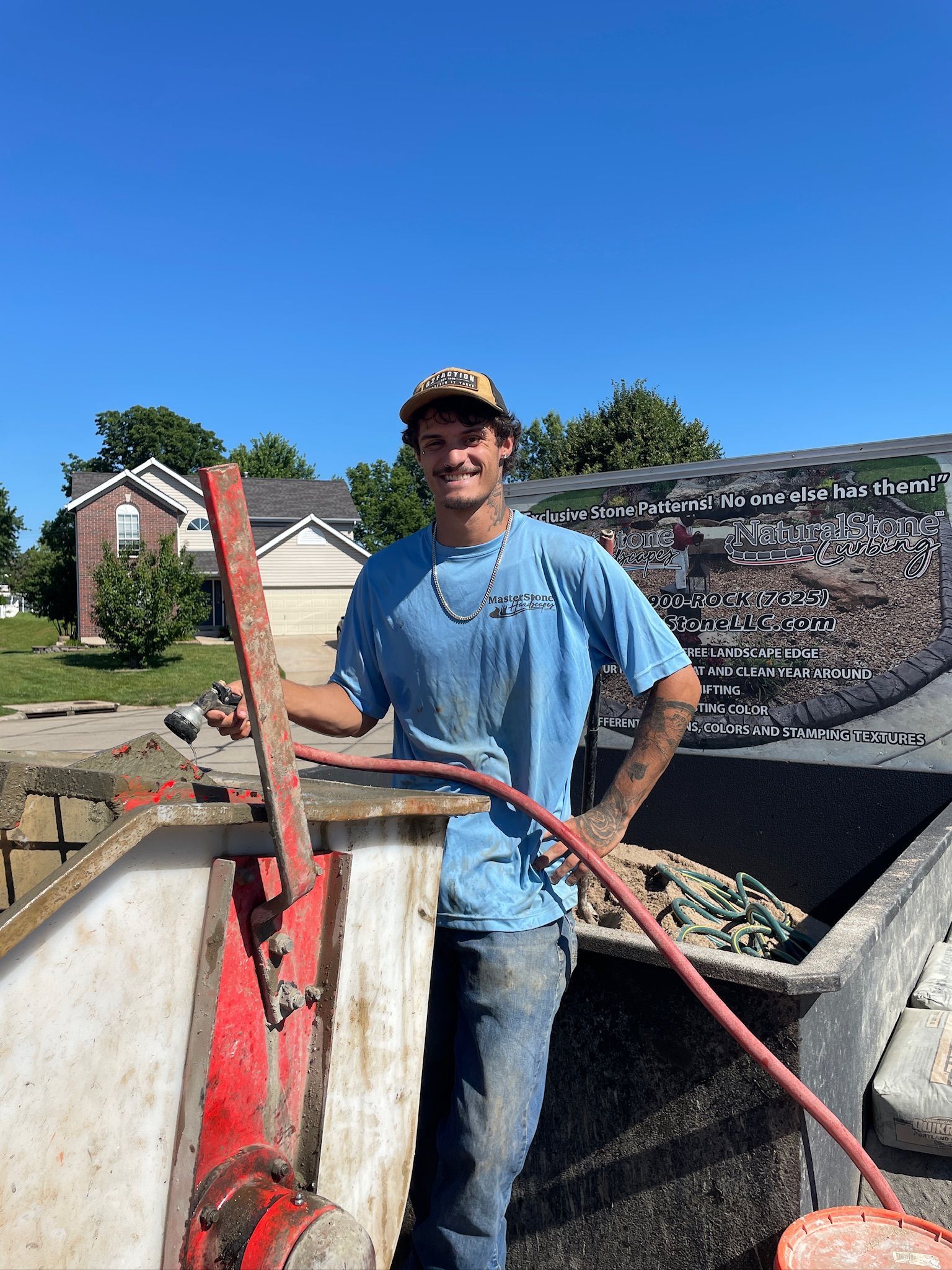 Worker standing on a construction truck beside a concrete mixer under a blue sky