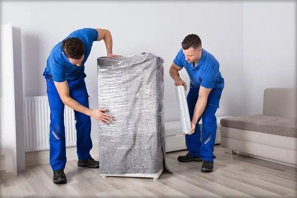 Two men wrapping a furniture