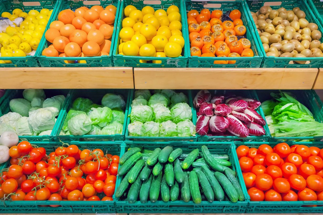 A grocery store shelf filled with lots of fruits and vegetables.