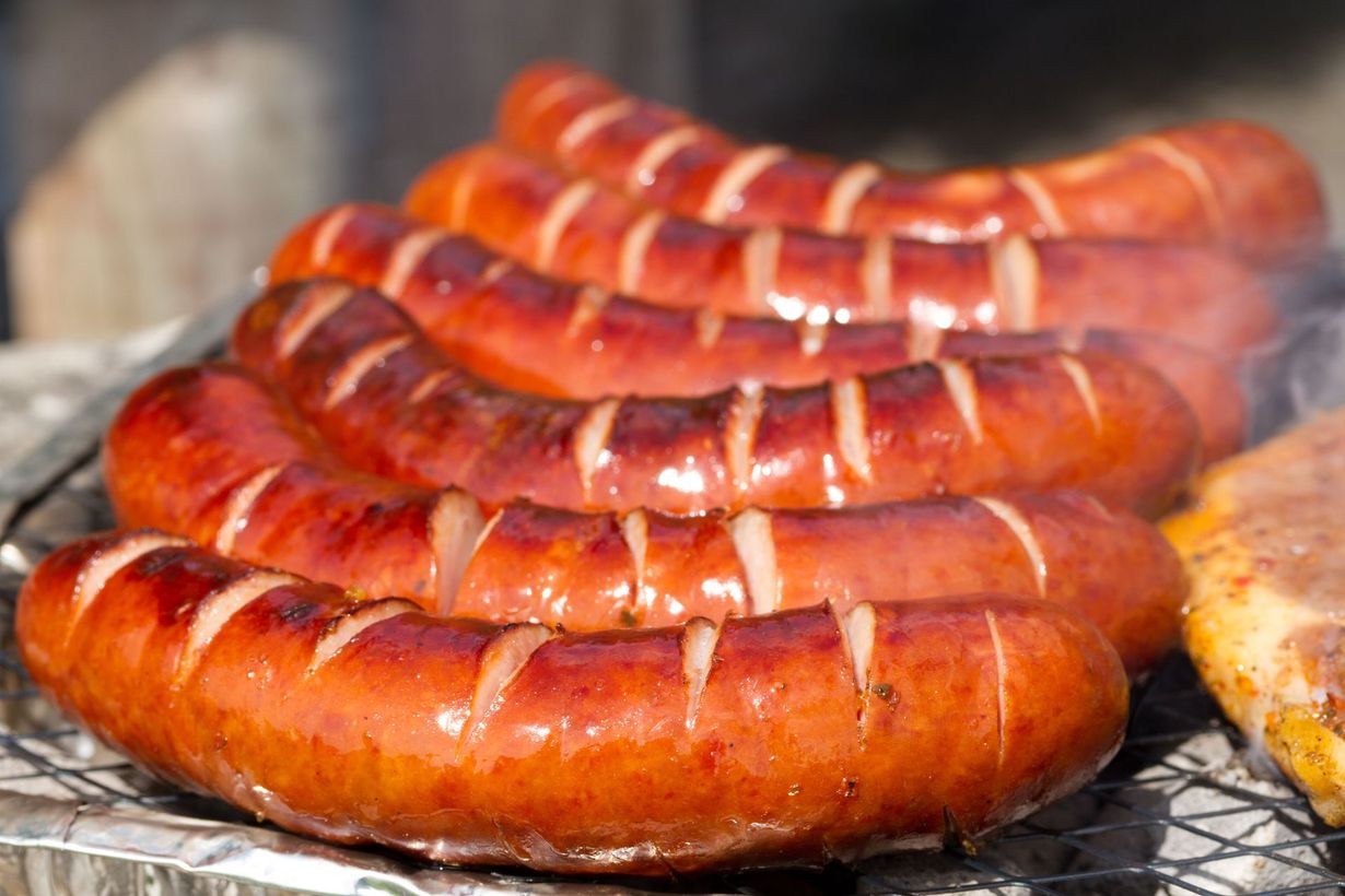 A bunch of sausages are cooking on a grill.