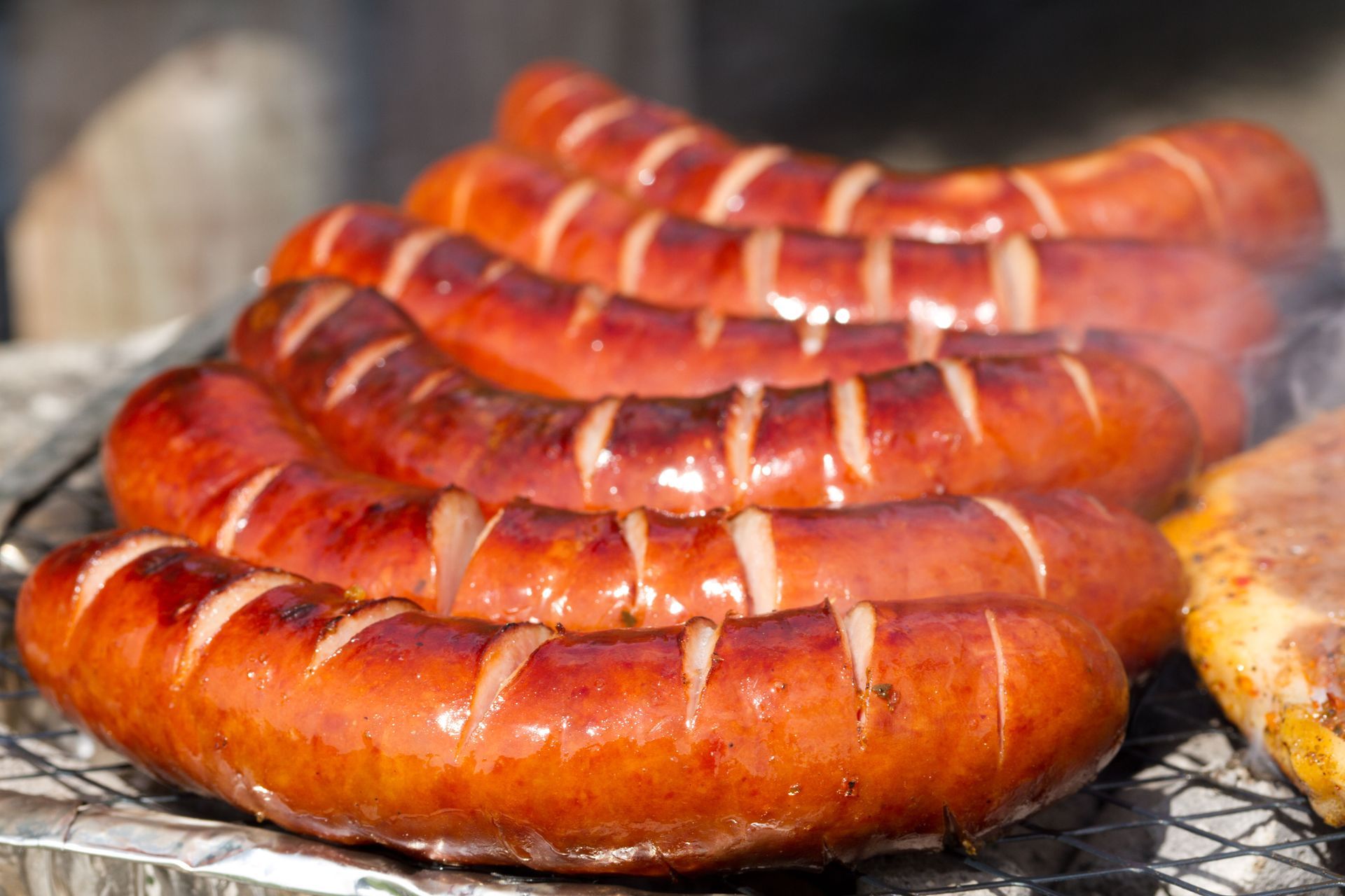 A bunch of sausages are cooking on a grill.